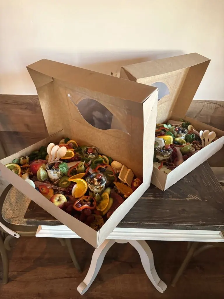 Geöffnete Cateringboxen mit Obst, Brot und Dessert